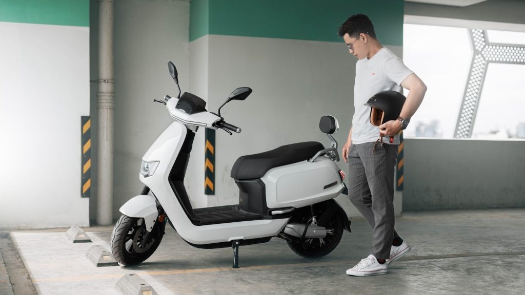 a man standing next to a white scooter